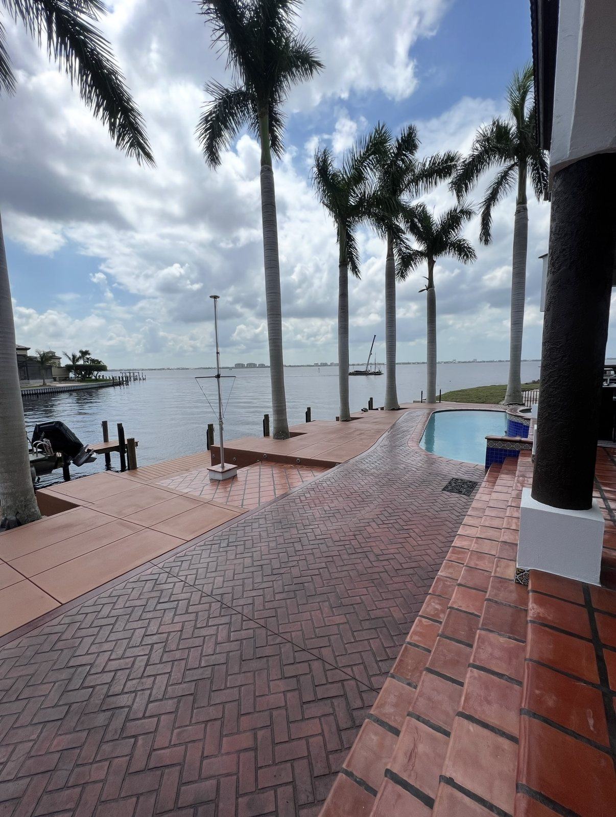Waterfront home with a stamped concrete pool deck and a concrete captain's walk along the seawall