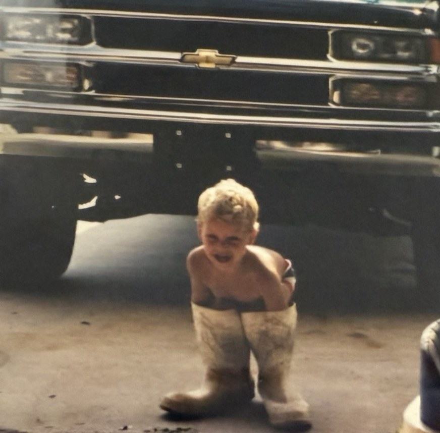 Syd Martin as a young boy in work boots in front of his family's concrete truck