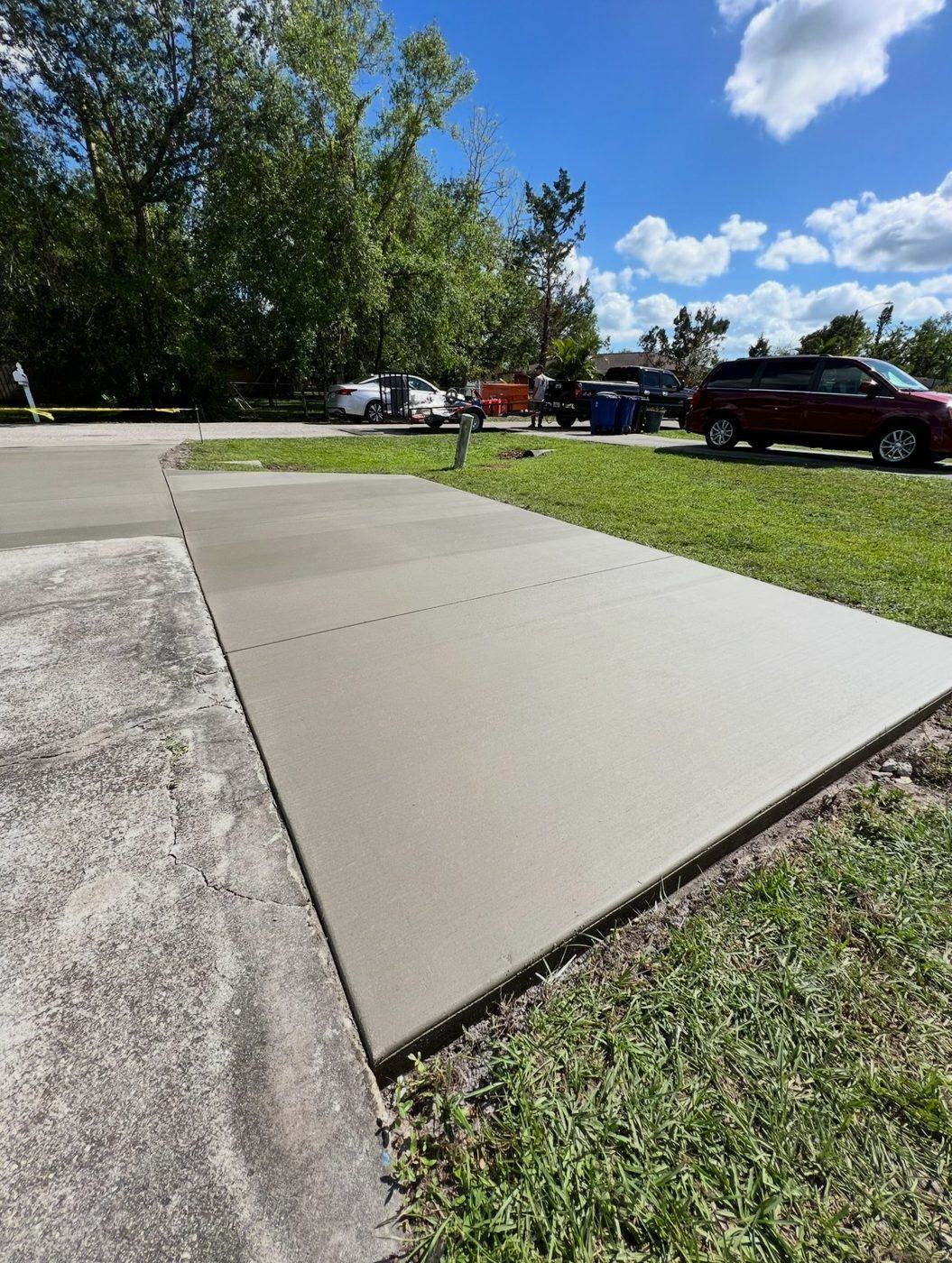 New broom-finish driveway extension beside an older driveway under mature trees, poured by Crete Concepts