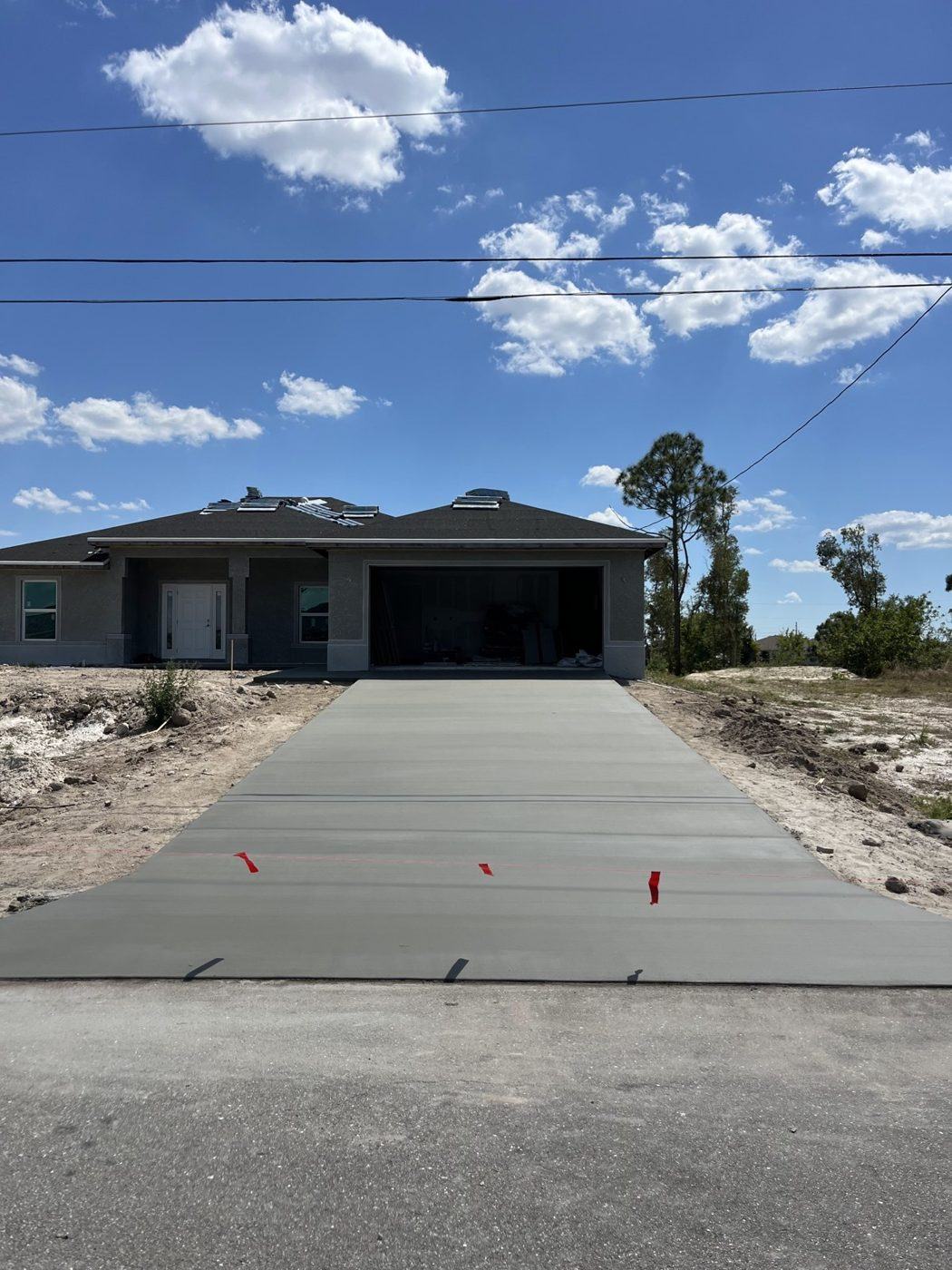 New concrete driveway at a recently built home on a sandy Southwest Florida lot, poured by Crete Concepts