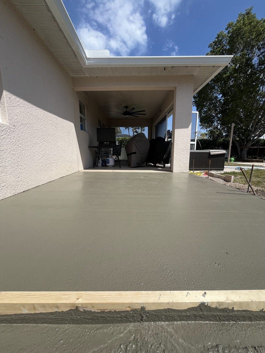 Freshly poured concrete patio extending from a covered lanai at a Southwest Florida home, by Crete Concepts